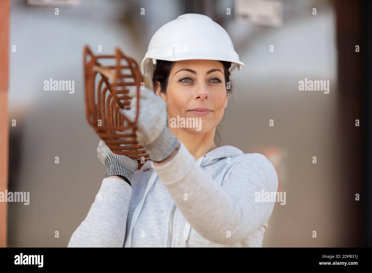 Bauarbeiterin, die mit Metallstruktur arbeitet Stockfoto