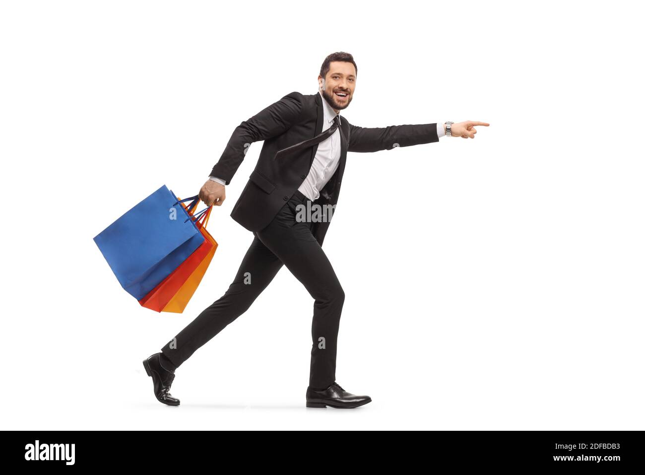 Mann in einem schwarzen Anzug läuft mit Einkaufstaschen und Zeigt isoliert auf weißem Hintergrund Stockfoto