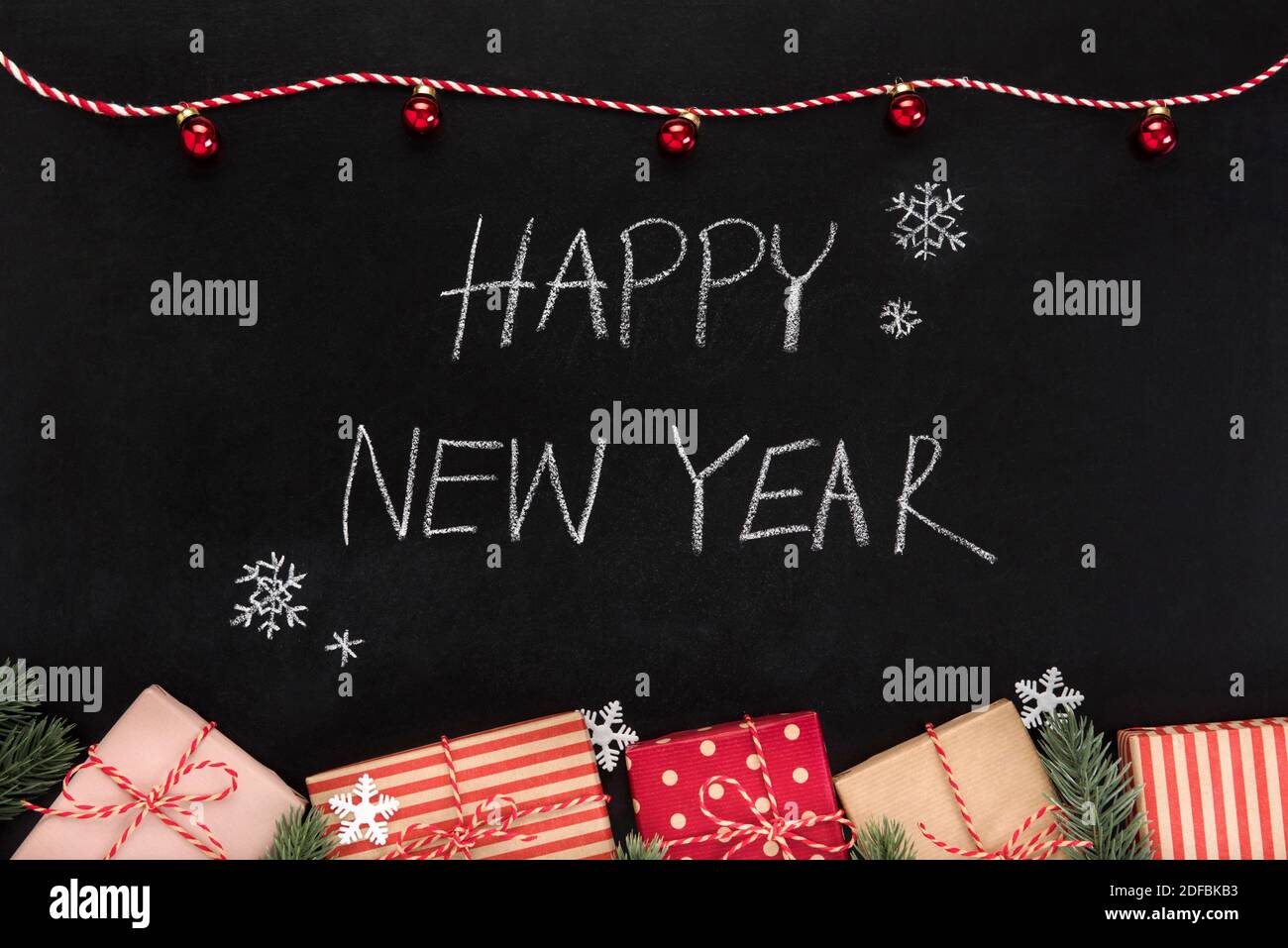 FROHES NEUES JAHR Hand schreiben Text auf Tafel mit Geschenk Schachteln und Weihnachtsschmuck Stockfoto