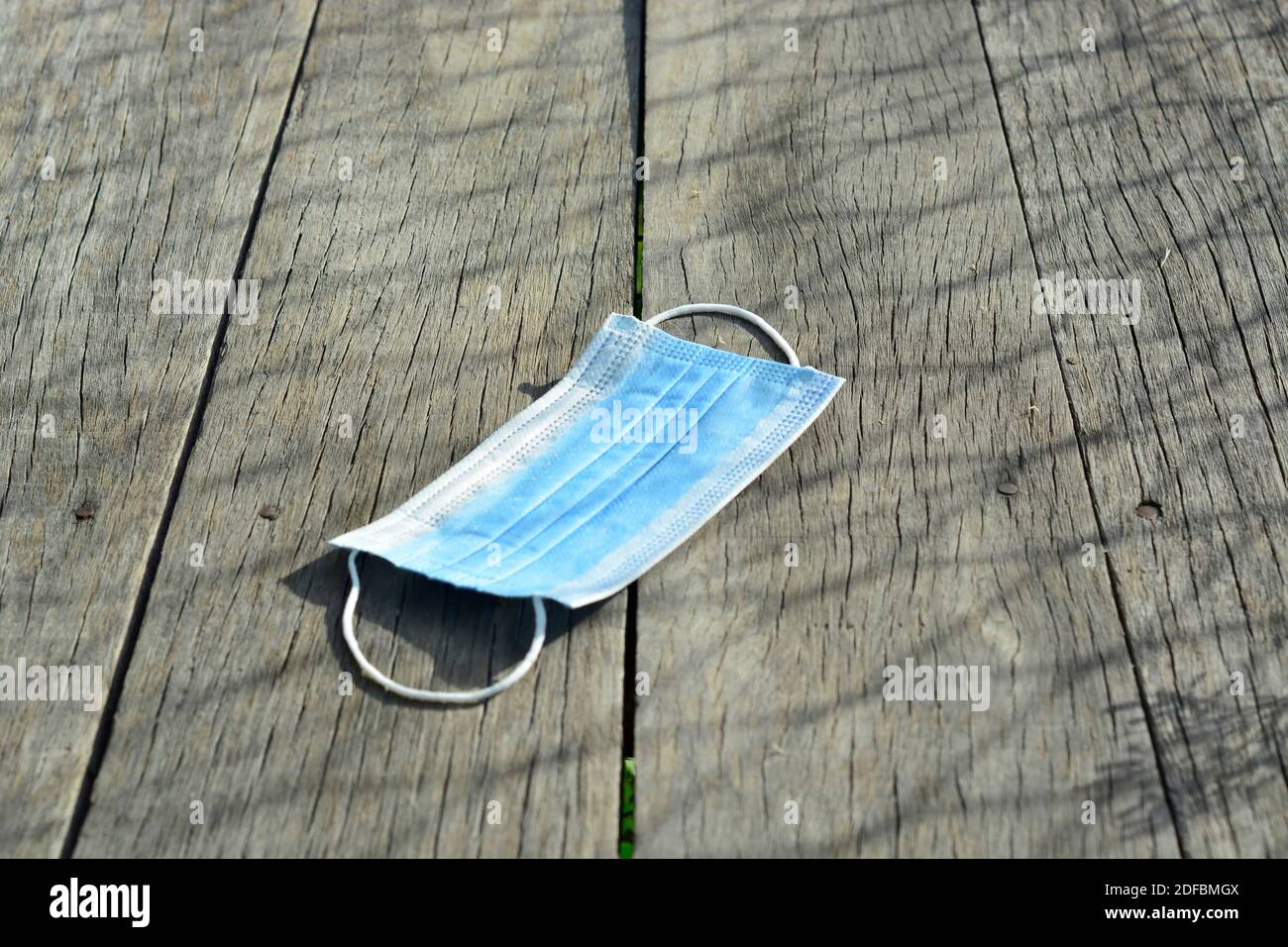 Facemask fallen auf Holzboden und unter das Sonnenlicht Stockfoto