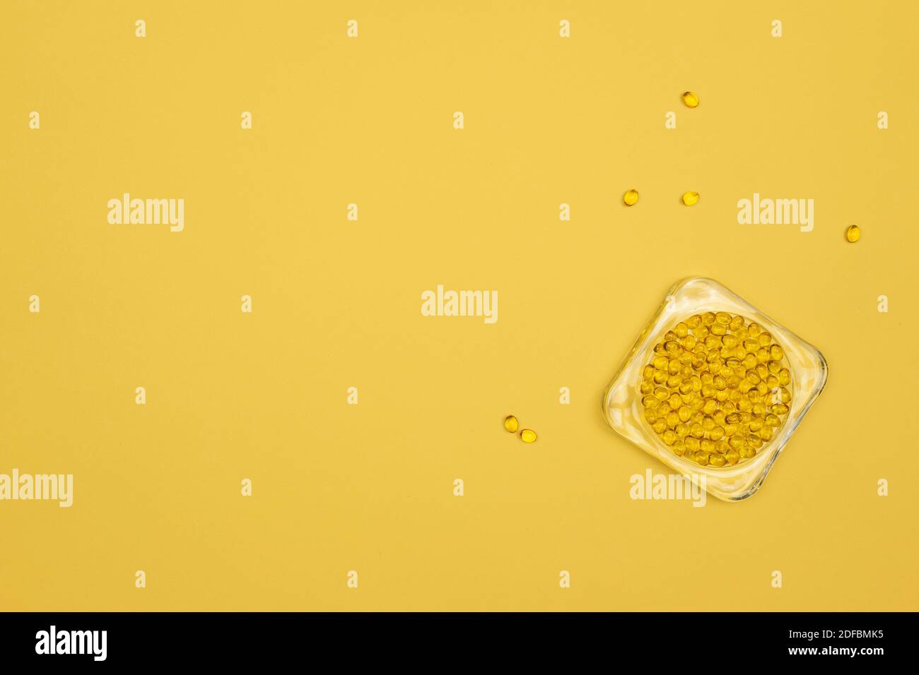 Kleine Kapseln von Omega 3 liegen auf gelbem Hintergrund Stockfoto