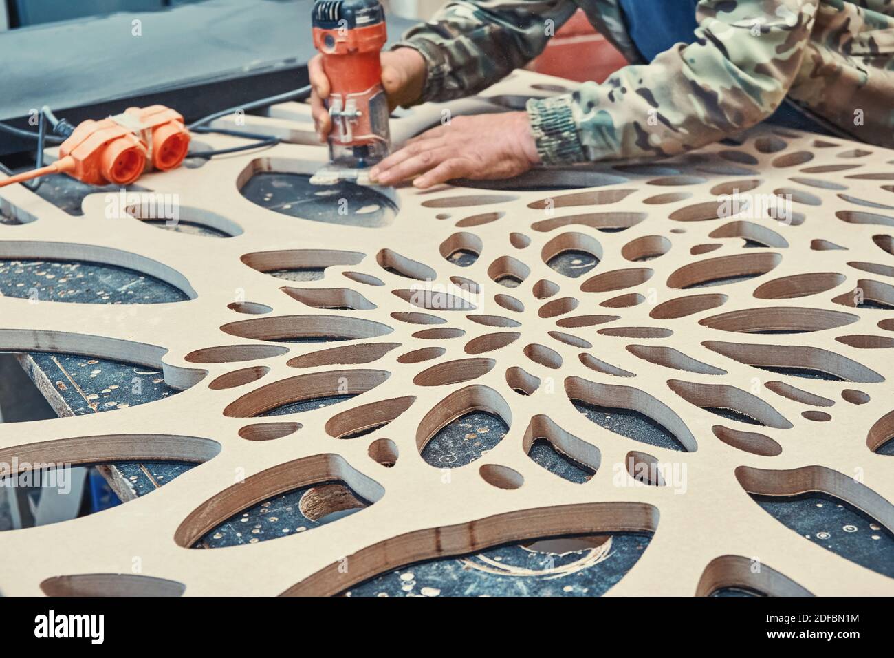 Dekorative Trennwand Herstellungsprozess. Tischlerfräsen Löcher in MDF mit  einer Hand elektrische Fräse Maschine. Dekorative Trennwand mit fl  Stockfotografie - Alamy