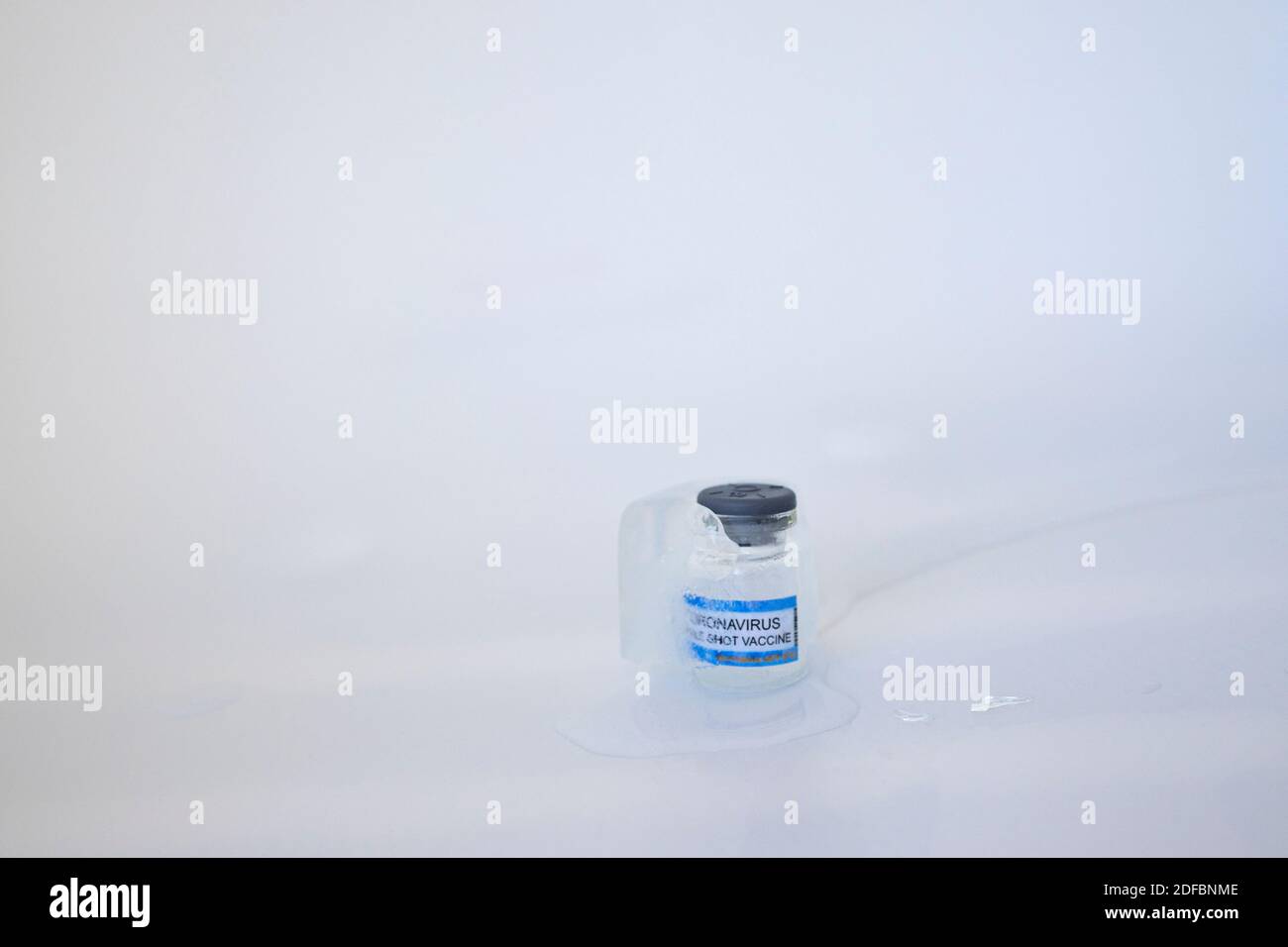 Langsam schmelzender Eiswürfel mit COVID-Impfstoff, eingefroren im Inneren Konzept von sehr niedrigen Lagertemperaturen für Corona-Virus-Impfstoff Glasfläschchen mit Vakuum Stockfoto