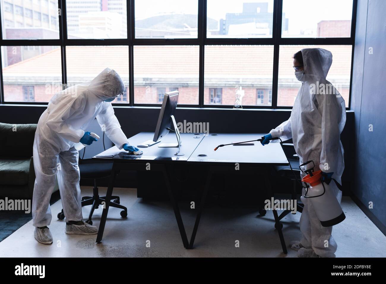 Gesundheitsarbeiter in Schutzkleidung Desinfektion kreativen Büro Stockfoto