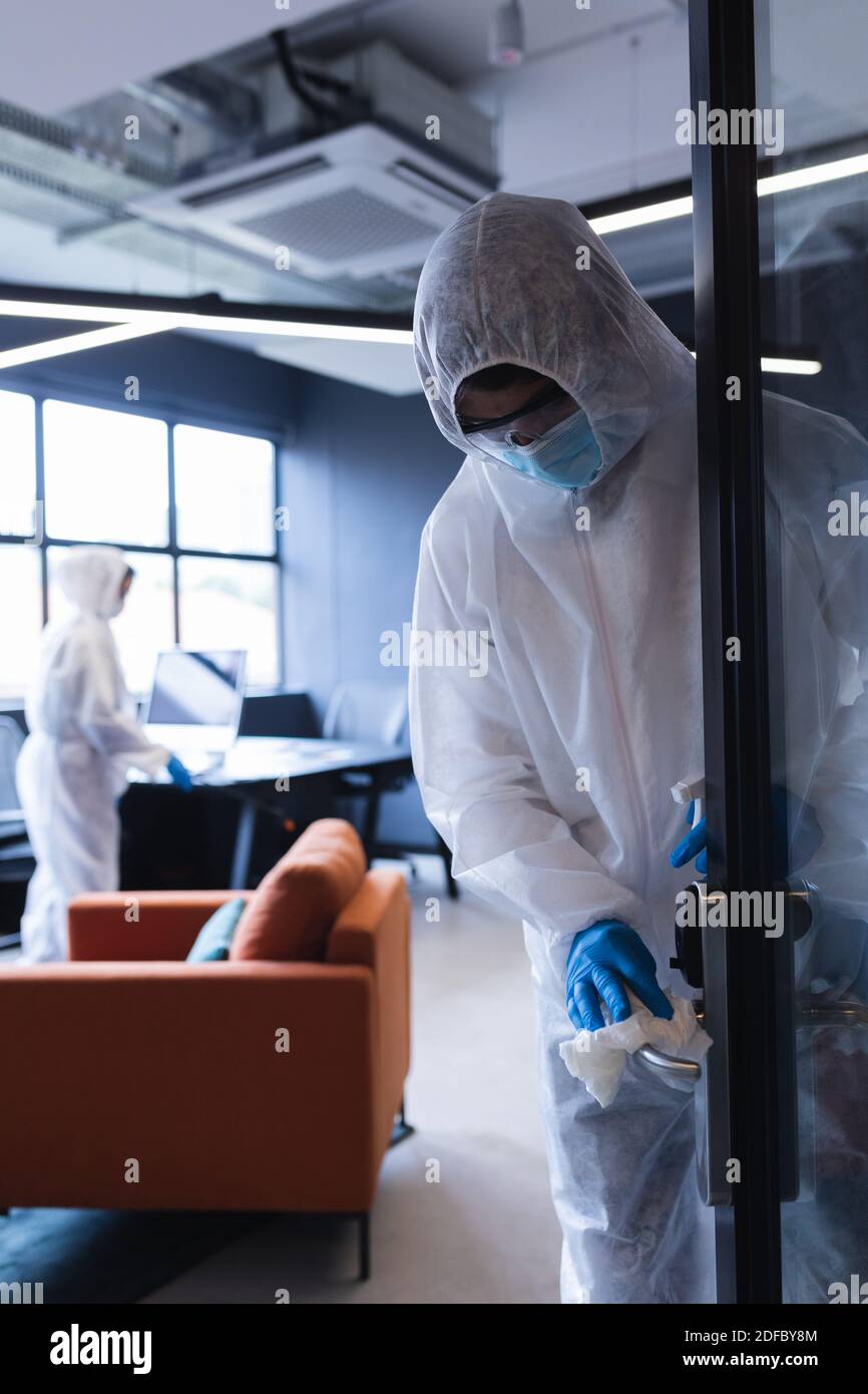 Gesundheitsarbeiter in Schutzkleidung Desinfektion kreativen Büro Stockfoto