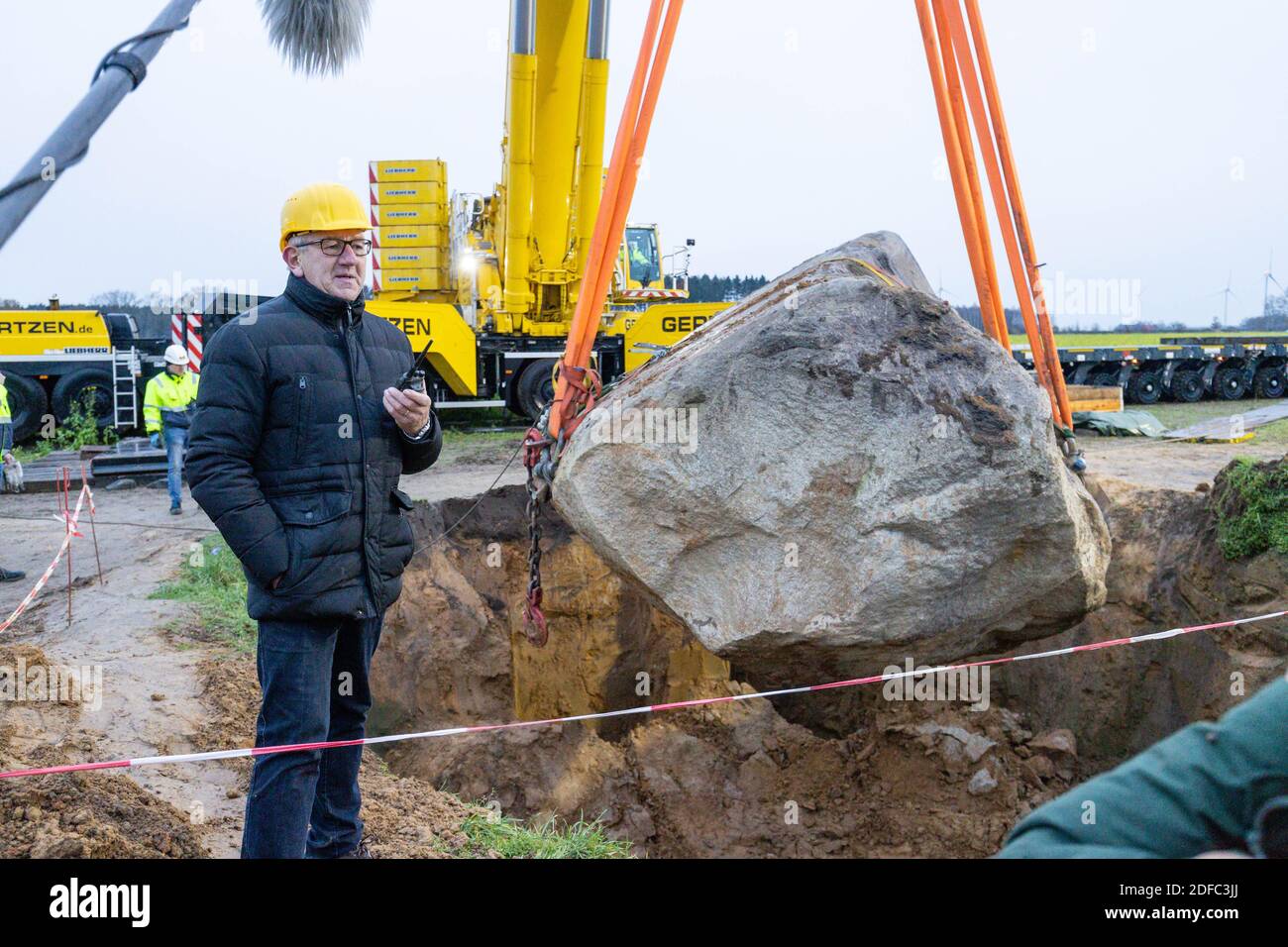 04. Dezember 2020, Niedersachsen, Hüven: Ein 102.5 Tonnen schwerer Stein wird von einem 800 Tonnen schweren Kran gehoben und auf einen Tieflader geladen. Eine Bauernfamilie hatte den unberechenbaren Block im Sommer freigelegt. Seitdem war der Ort zu einer Attraktion für Tausende von Zuschauern geworden. Foto: Martin Remmers/dpa Stockfoto