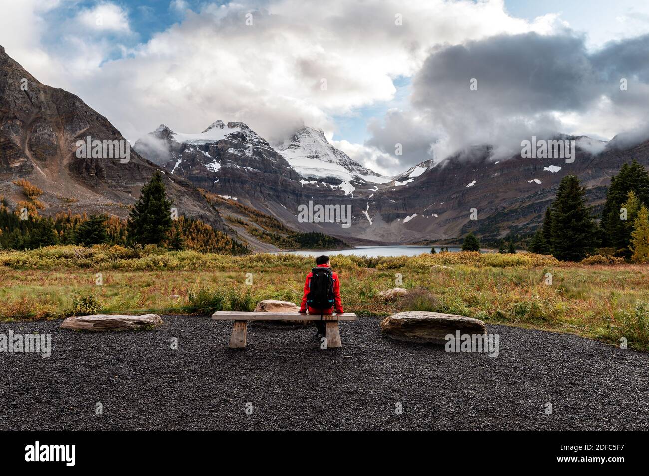 Reisender Mann sitzt am Strand mit Berg assiniboine und See magog in Provincial Park am Morgen Stockfoto