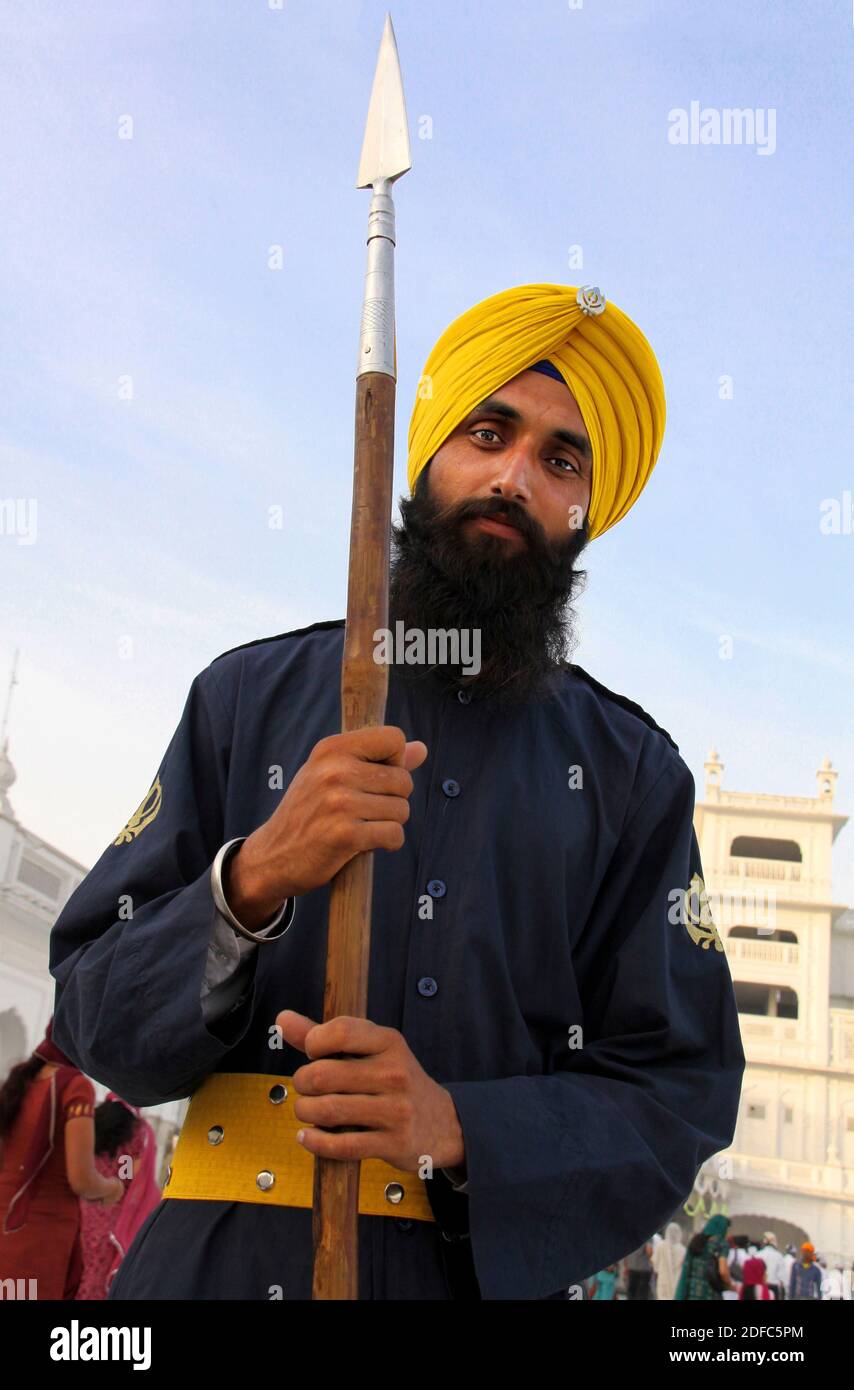 Indien, Amritsar, Sikh Mann mit Speer und safranfarbenen Turban im goldenen Tempel Stockfoto