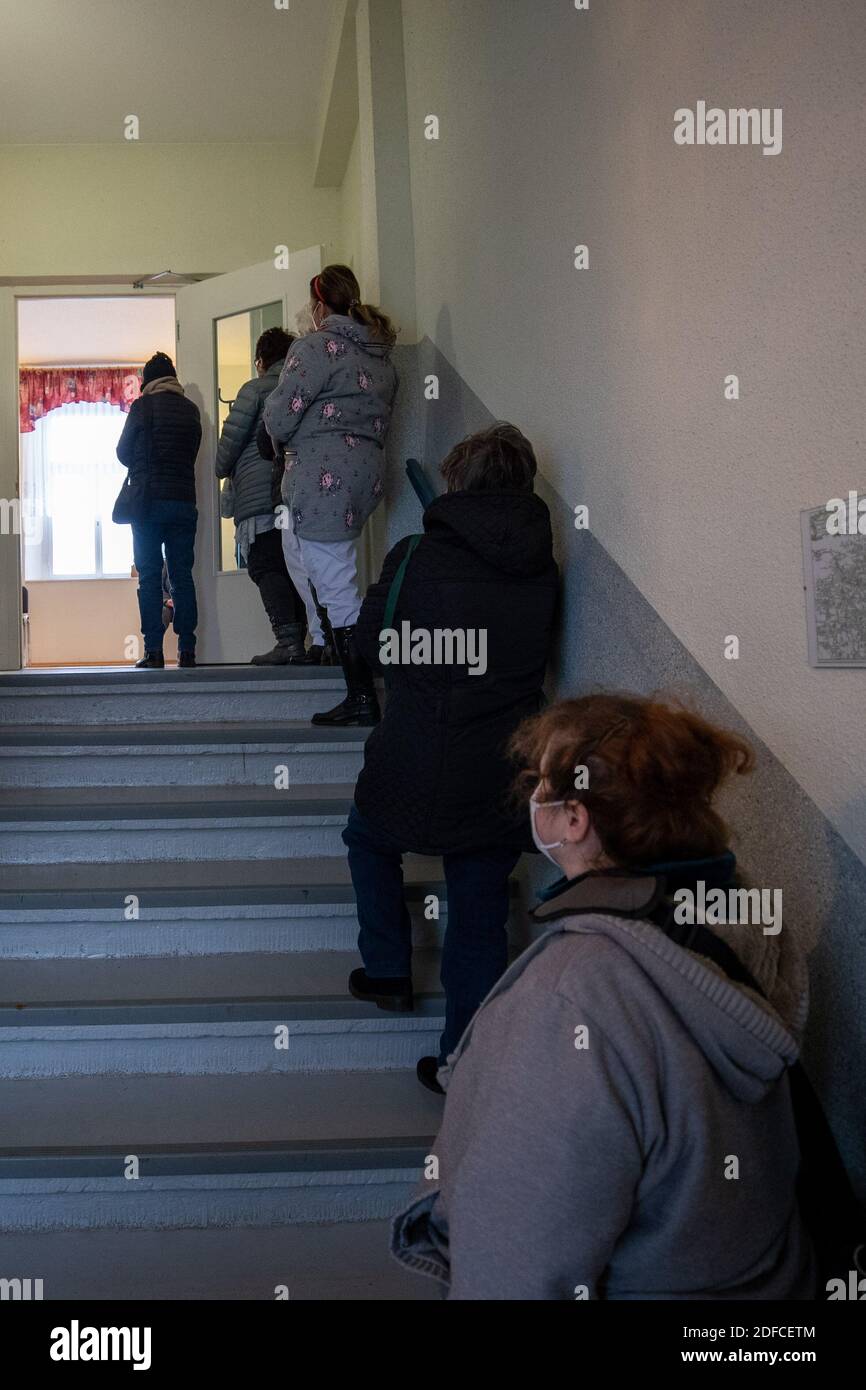 Rathmannsdorf, Deutschland. Dezember 2020. Menschen, die getestet werden wollen, warten im Treppenhaus des Gemeindezentrums. Die Bewohner der Gemeinde Rathmannsdorf im Landkreis Sächsische Schweiz-Osterzgebirge werden auf das SARS-CoV-2-Virus (Coronavirus) getestet. Das Sächsische Staatsministerium für Soziales und sozialen Zusammenhalt (SMS) will mit dieser Kampagne Wissen über die Verbreitung des Virus in fünf ausgewählten Bezirken gewinnen. Quelle: Daniel Schäfer/dpa-Zentralbild/dpa/Alamy Live News Stockfoto