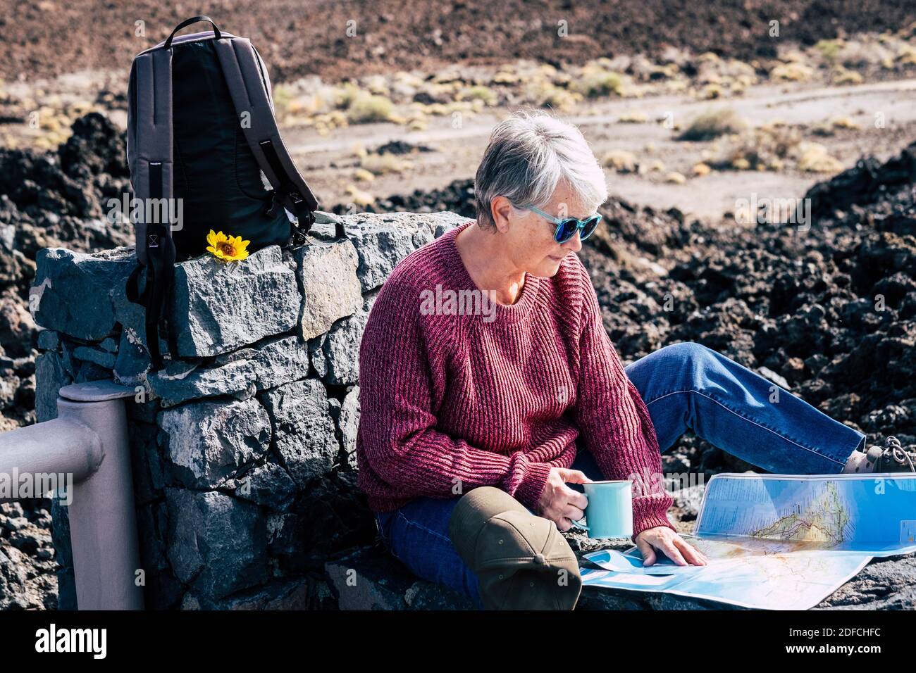 Aktive Senioren Ruhestand Lebensstil mit schönen reifen kaukasischen Dame sitzen Unten im Outdoor-Reise-Rucksack alternative Urlaub und Freizeitaktivitäten Stockfoto
