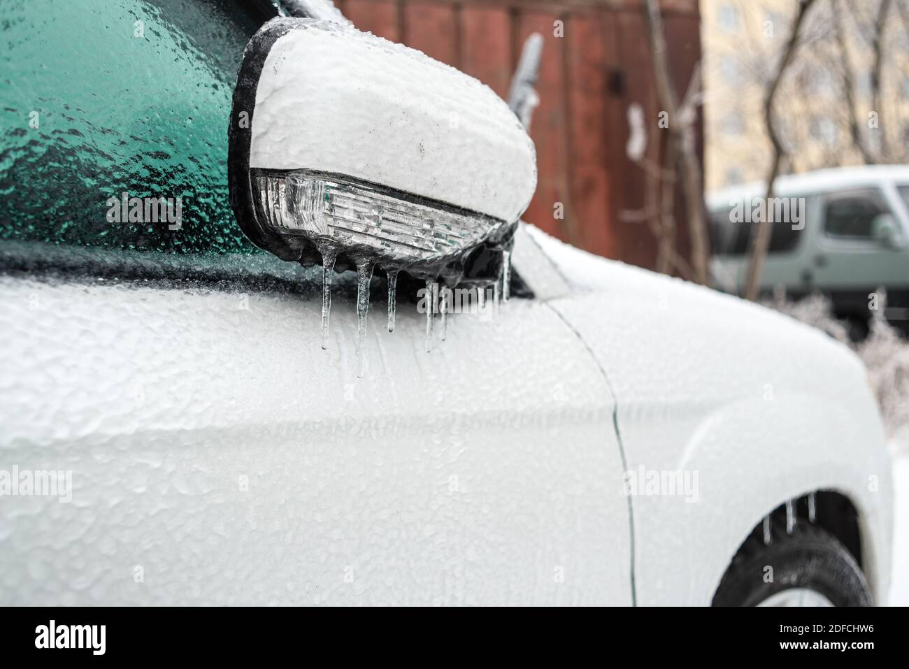 Eisbedecktes Autofenster aus der Nähe. Auto mit Eis und Eiszapfen nach Glatteisregen bedeckt. Schlechtes Winterwetter, Eissturm. Stockfoto