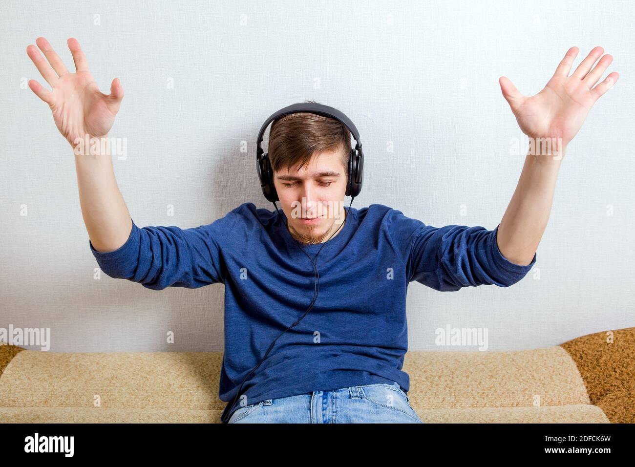 Glücklicher junger Mann in den Kopfhörern Hören Sie die Musik An der Wand Stockfoto