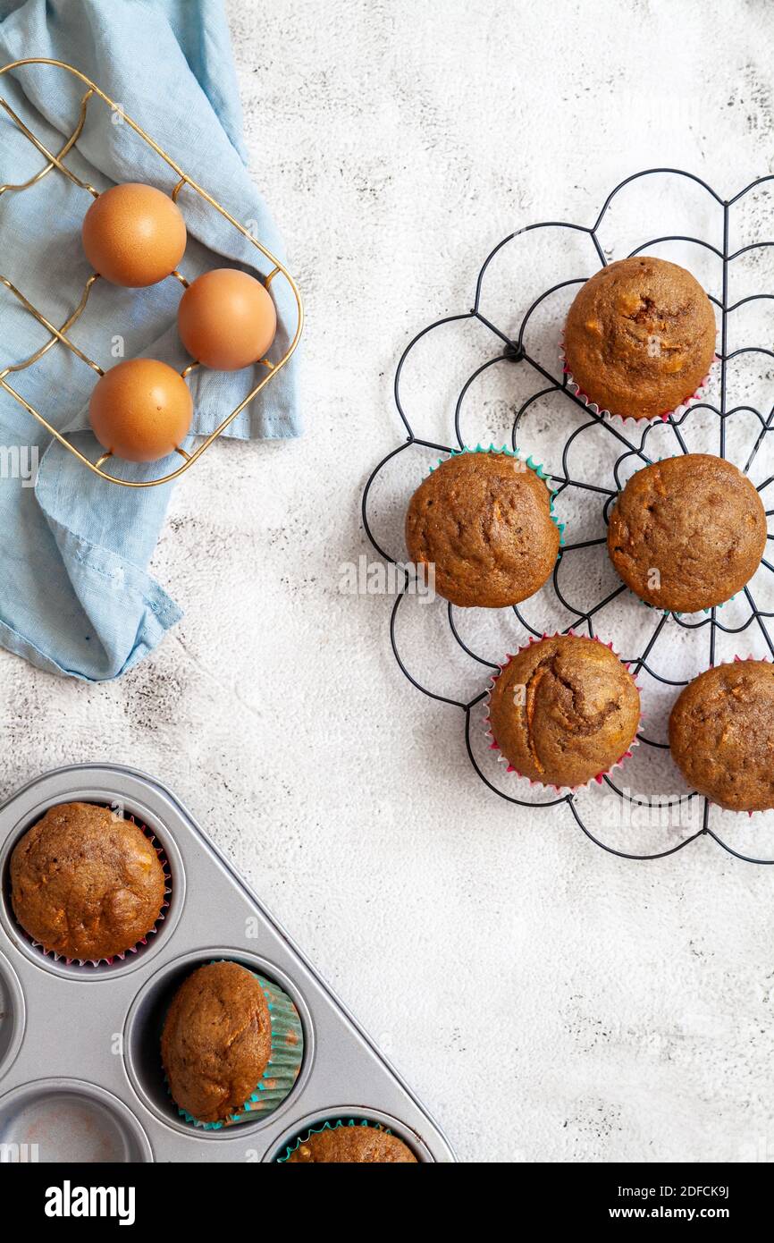 Muffins auf einem schwarzen Kühlregal mit Eiern in einem Korb und ein Backblech mit gebackenen Muffins Stockfoto