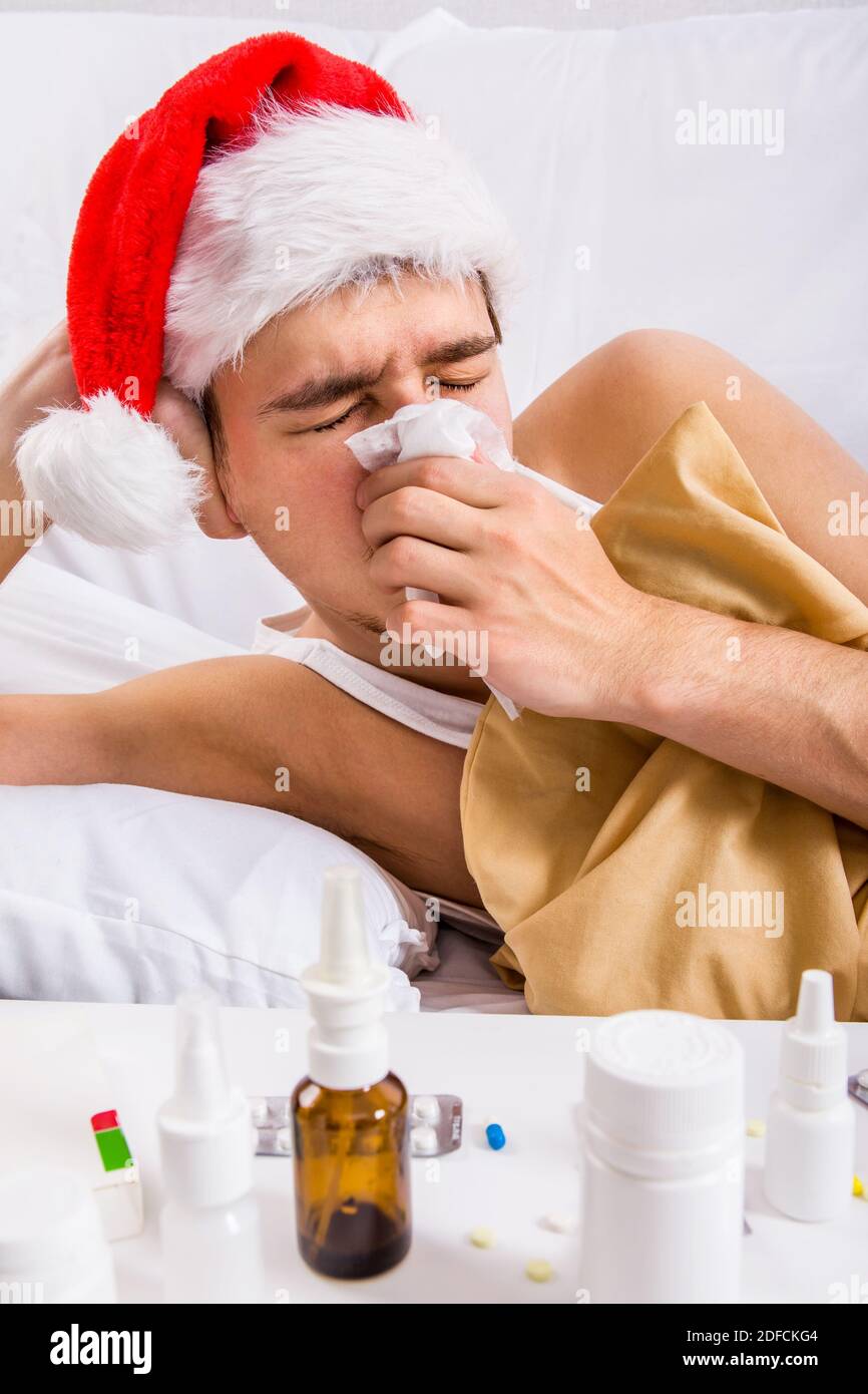 Kranker Mann in Santa hat mit einem Taschentuch in der Bett im Haus Stockfoto