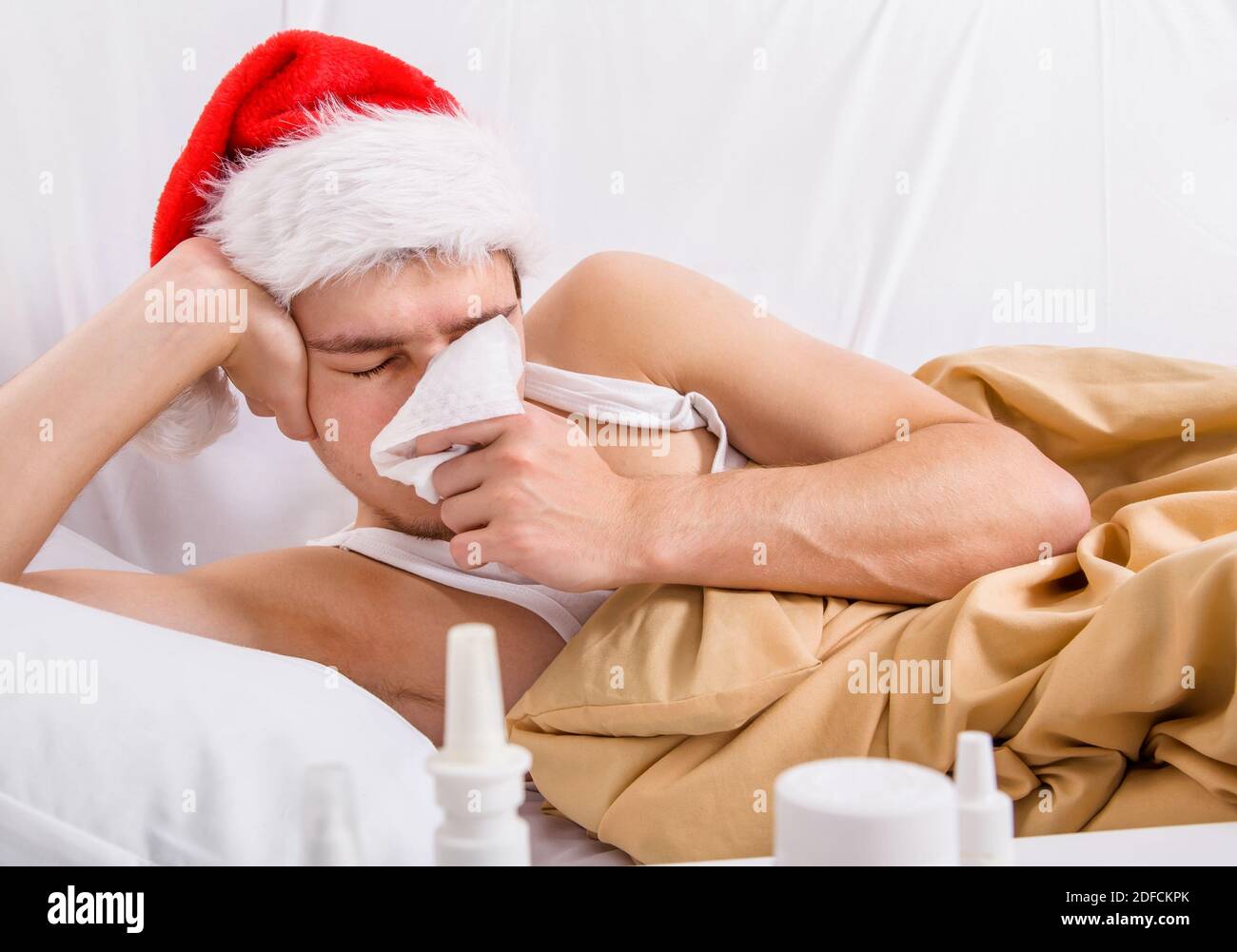 Kranker Mann in Santa hat mit einem Taschentuch in der Bett im Haus Stockfoto