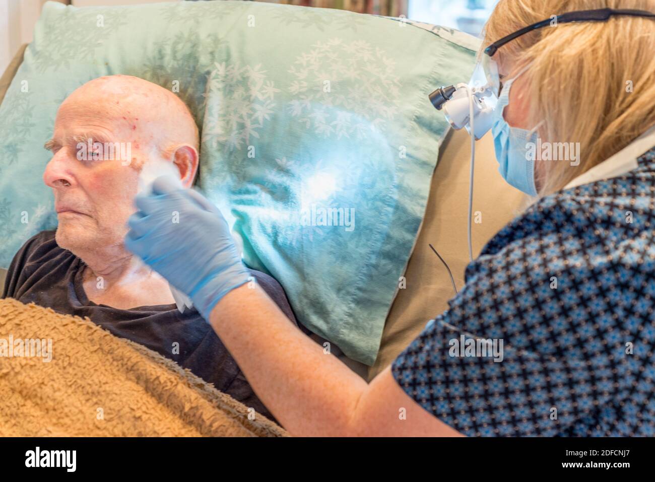 Bettlägiger älterer Mann, der sich lange einer unangenehmen, aber notwendigen Behandlung unterziehen muss Begriff Aufbau von Ohrenschmalz, verdichtet über die Ohrtrommel und Im Ohr Stockfoto