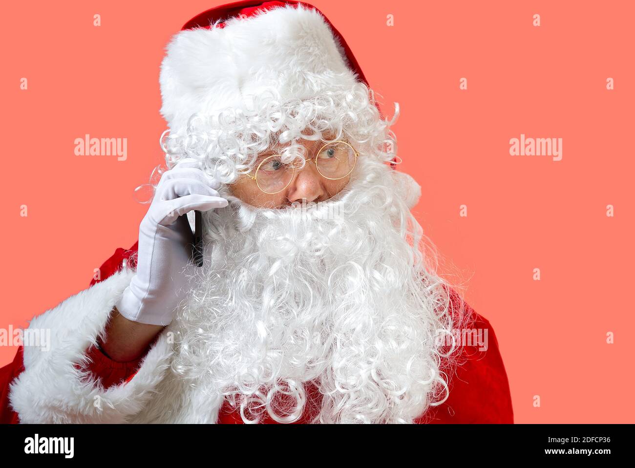 weihnachtsmann mit Handy isoliert auf rosa Hintergrund Stockfoto