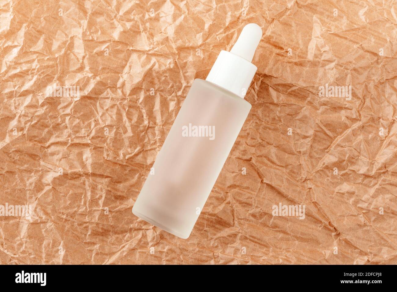 Hyaluronsäure-Tinktur auf gefaltetes Karton. Serum mit Kollagen und Peptiden auf zerknittertem Papier. Anti-Age-Produkt, Luxus-Körperpflege-Konzept Stockfoto
