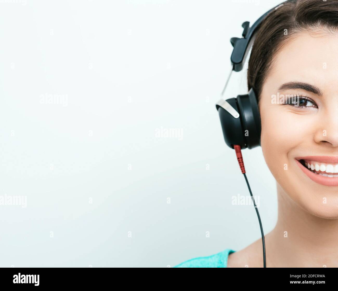 Mixed Race Frau mit toothy Lächeln bekommen einen Hörtest, Audiometer Hörtest. Halbfläche, auf grauem Hintergrund Stockfoto