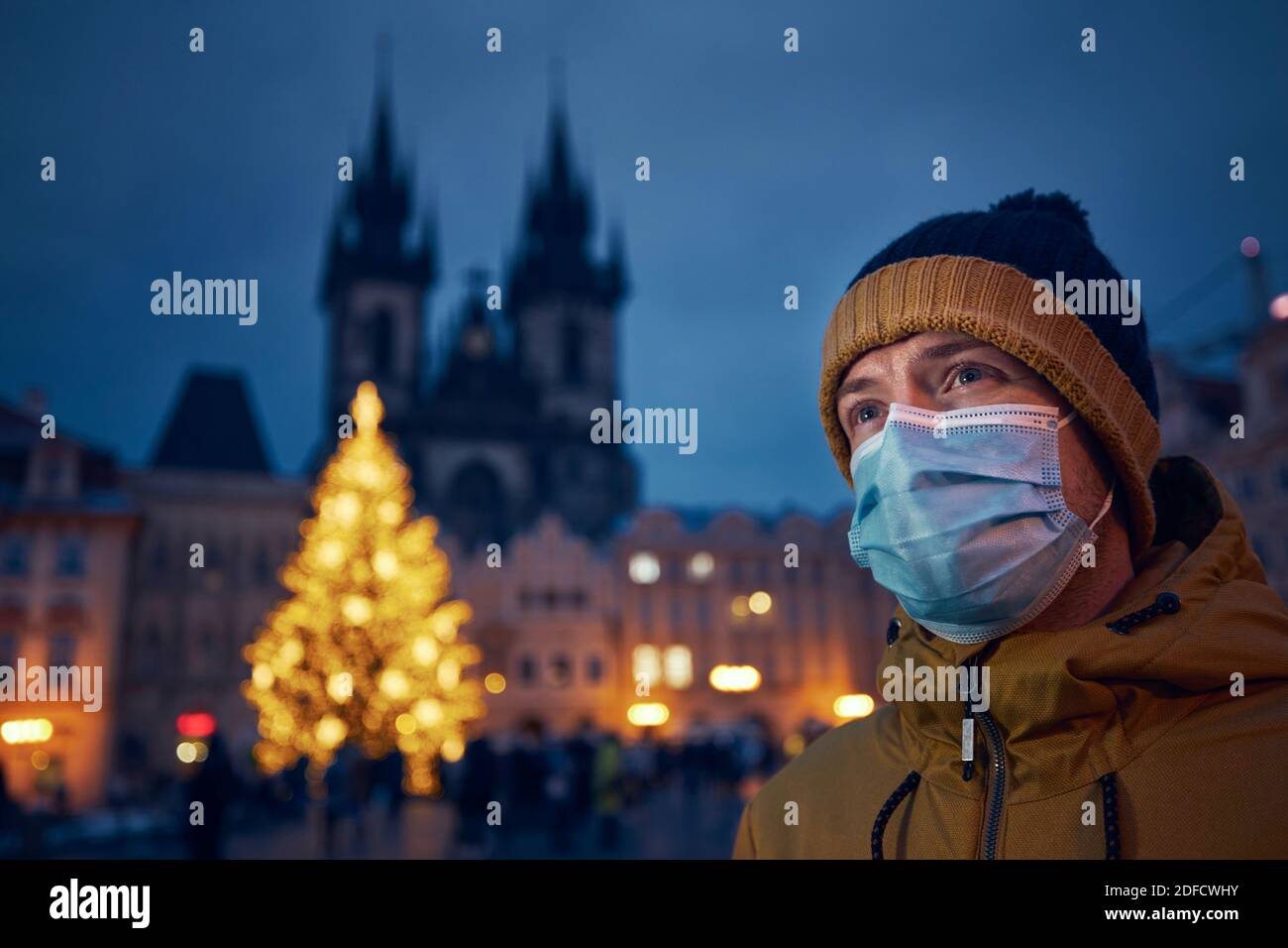 Junger Mann mit Gesichtsmaske gegen Weihnachtsbaum in Prag. Themen Coronavirus-Pandemie während der Weihnachtsfeiertage und persönliche Verantwortung. Stockfoto