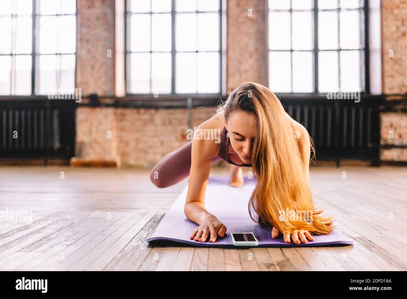 Junge Langhaarige Frau Tun Komplex Von Stretching Yoga Asanas Im Loft Stil Sonnigen Klasse Mit Ihrem Smartphone Online Unterricht Und Training Stockfotografie Alamy