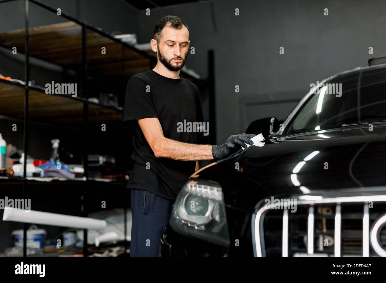 Junger Mann, Car Polish Service Worker Polieren Autohaube, Polieren und Polieren Fahrzeug mit Nano-Keramik-Zusammensetzung oder Wachs. Details zum Fahrzeug. Tools für Stockfoto
