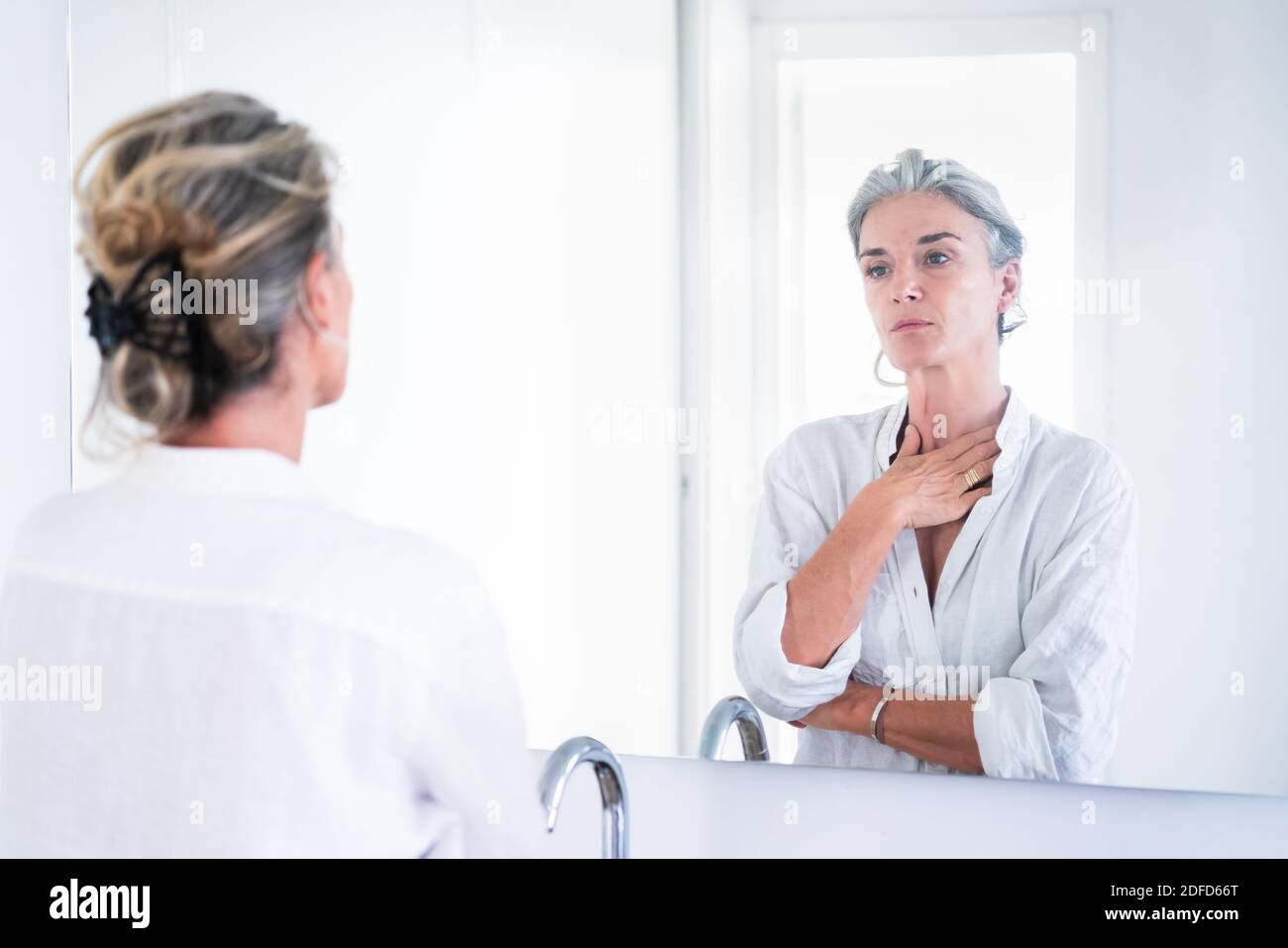 Porträt einer älteren Frau, die sich in einem Spiegel ansieht. Stockfoto