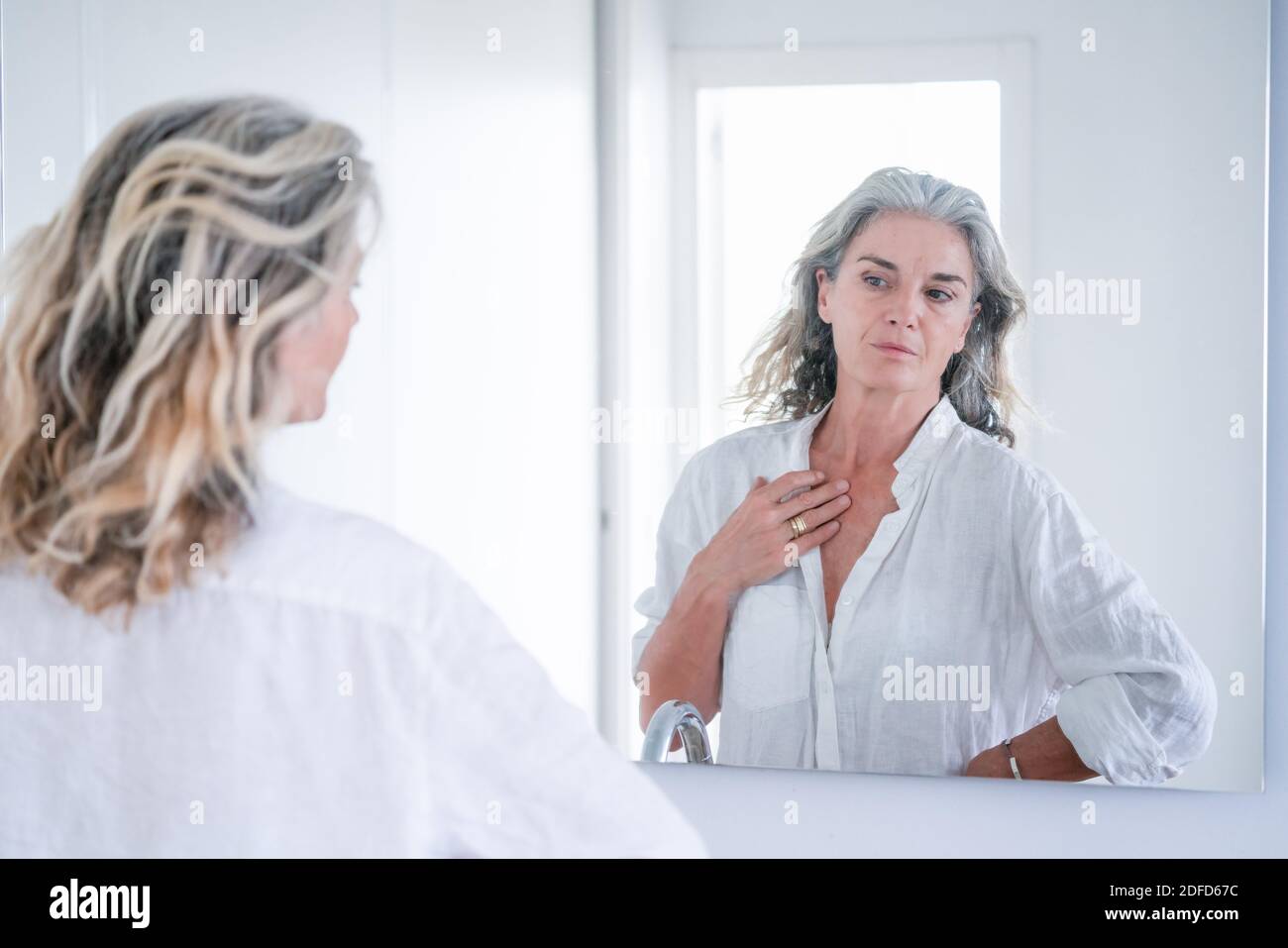 Porträt einer älteren Frau, die sich in einem Spiegel ansieht. Stockfoto