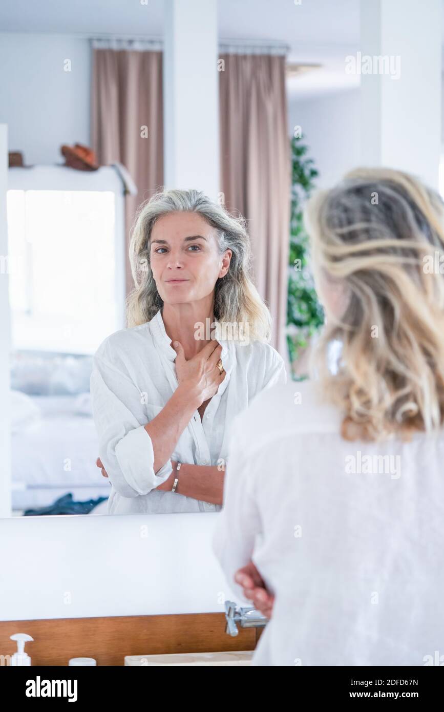 Porträt einer älteren Frau, die sich in einem Spiegel ansieht. Stockfoto