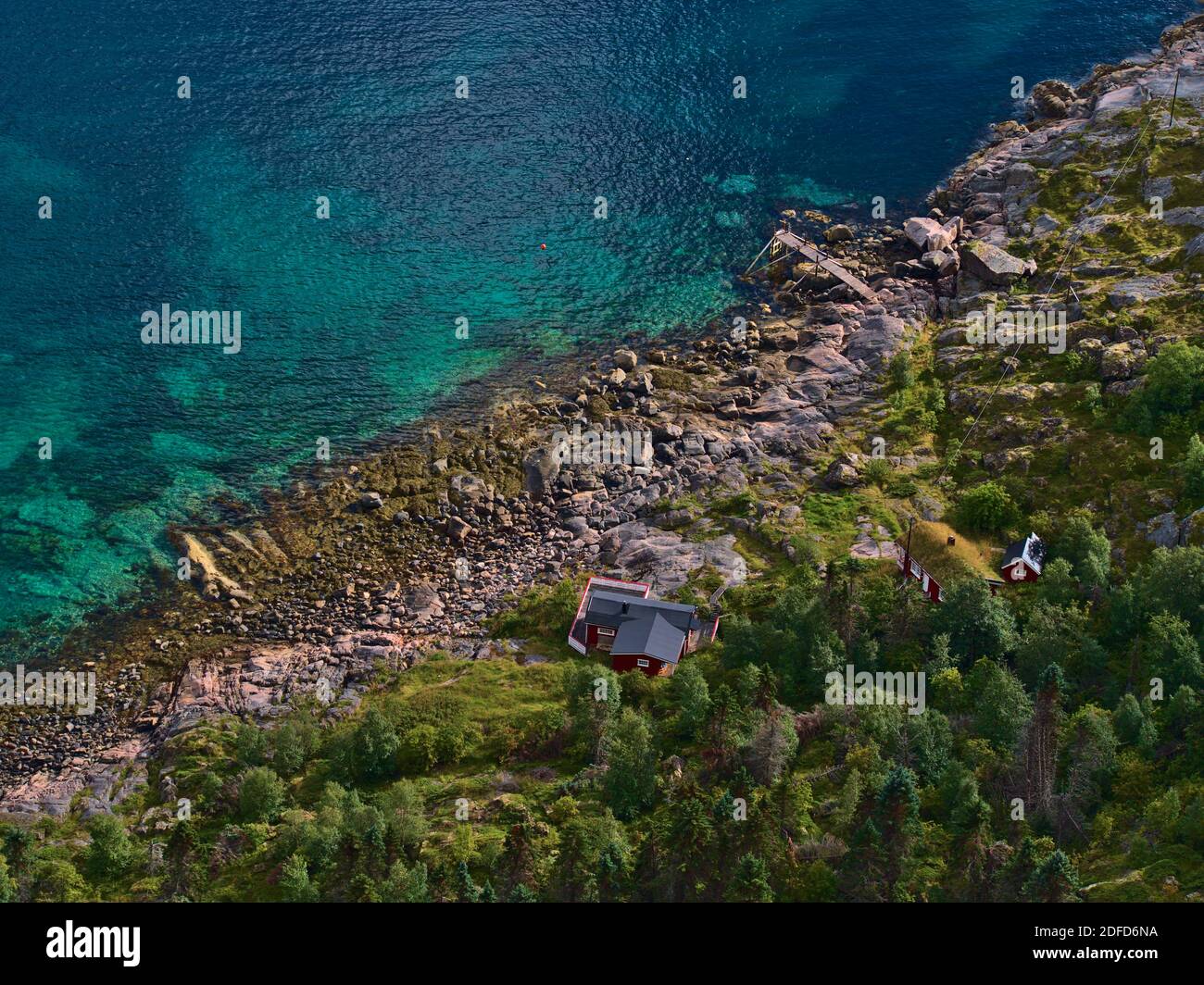 Schöne Luftaufnahme der traditionellen norwegischen Holzhäuser mit roter Fassade an der felsigen Küste der Insel Austvågøya in der Nähe von Henningsvær, Lofoten. Stockfoto
