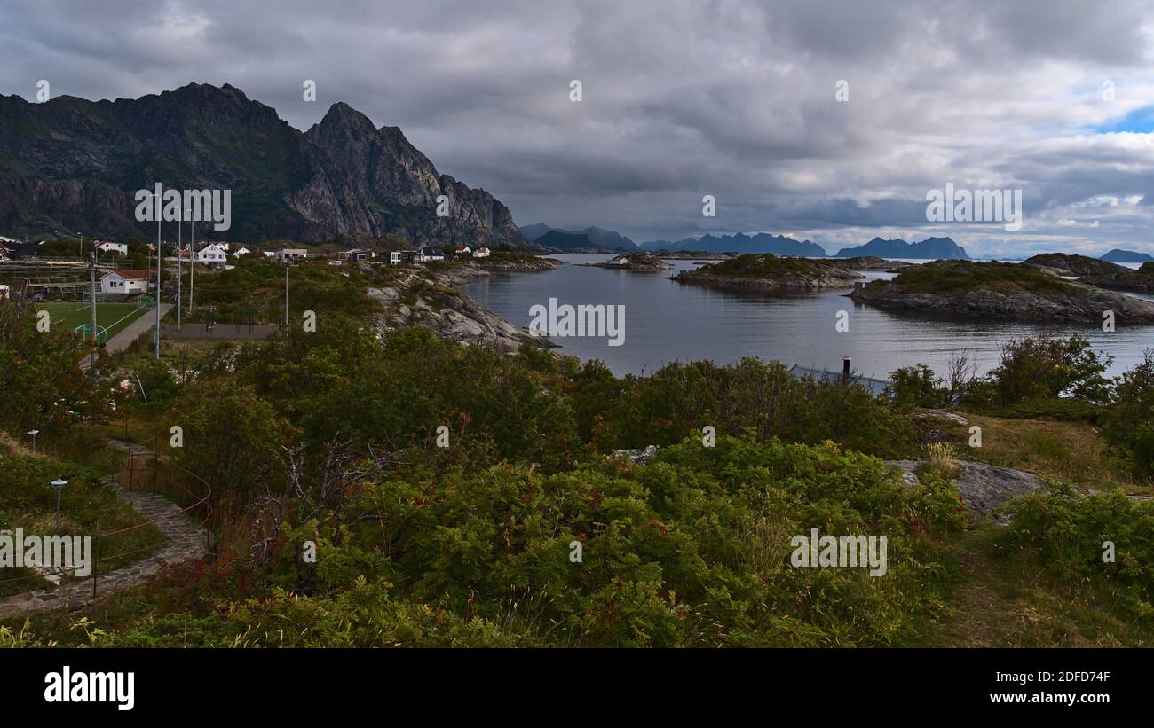 Schöne Aussicht auf die zerklüfteten Berge an der Küste der Insel Austvågøya, Lofoten, Norwegen mit Fischerdorf Henningsvær, Fußballplatz und Häusern. Stockfoto
