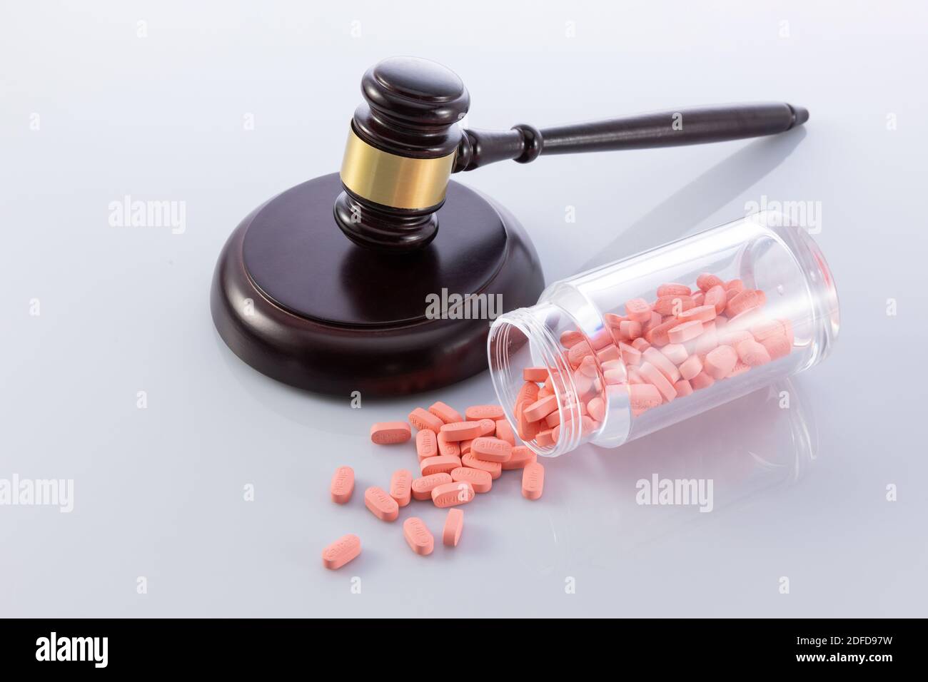 Ein Nahaufnahme des Gavels des Richters und der fallenden Pillen Aus dem Glas - das Konzept des illegalen Verkaufs der Medikamente Stockfoto