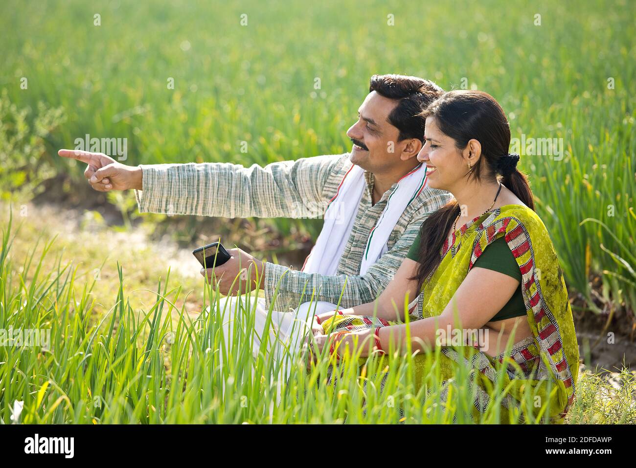 Glückliche indische Paar Bauern Untersuchung Ernte im Feld Stockfoto