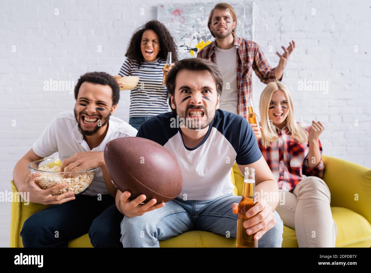 Multikulturelle Rugby-Fans mit gemalten Gesichtern Grimacing beim Ansehen der Meisterschaft Zu Hause Stockfoto