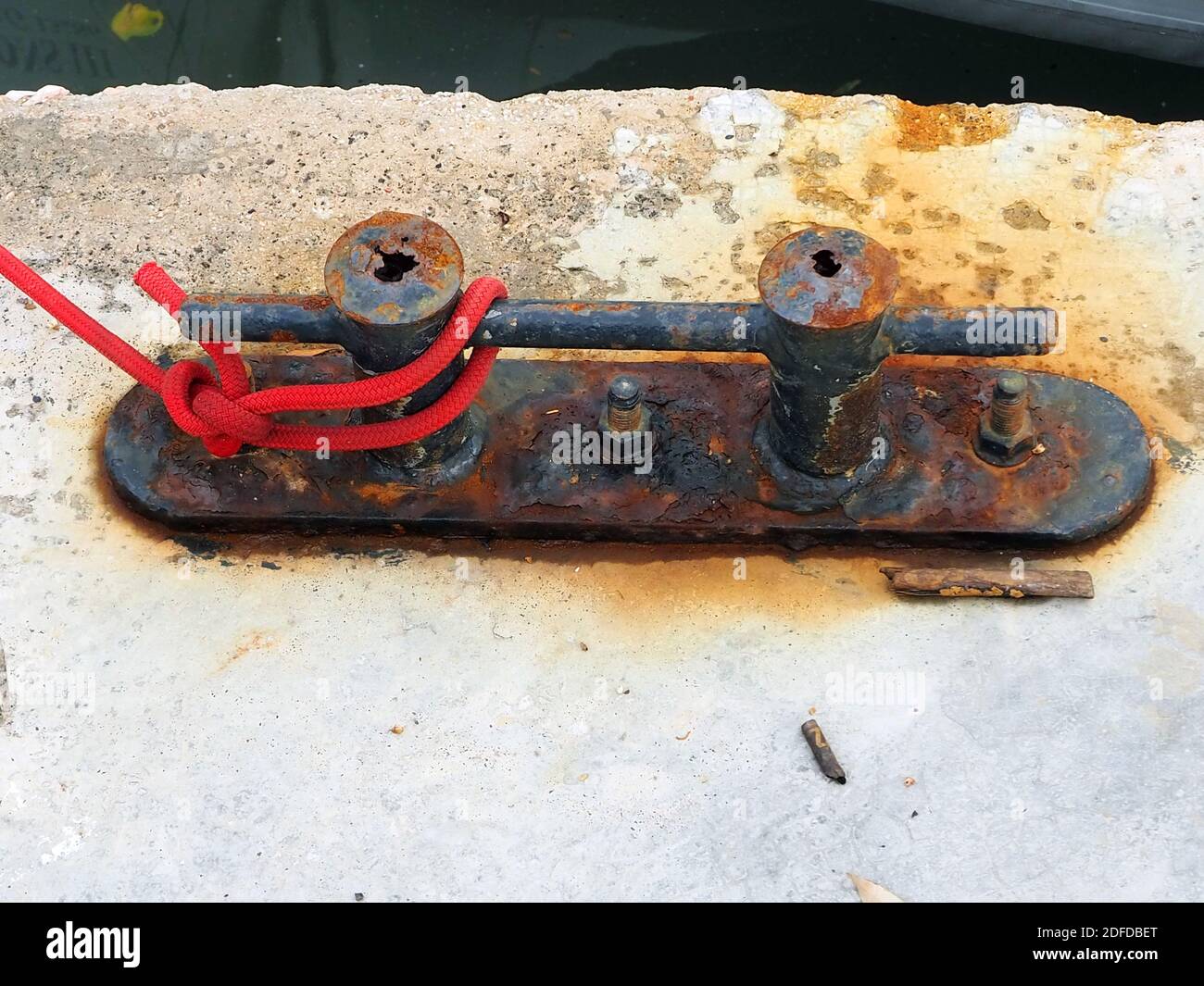 Rostiger Poller mit rotem Seil Stockfoto