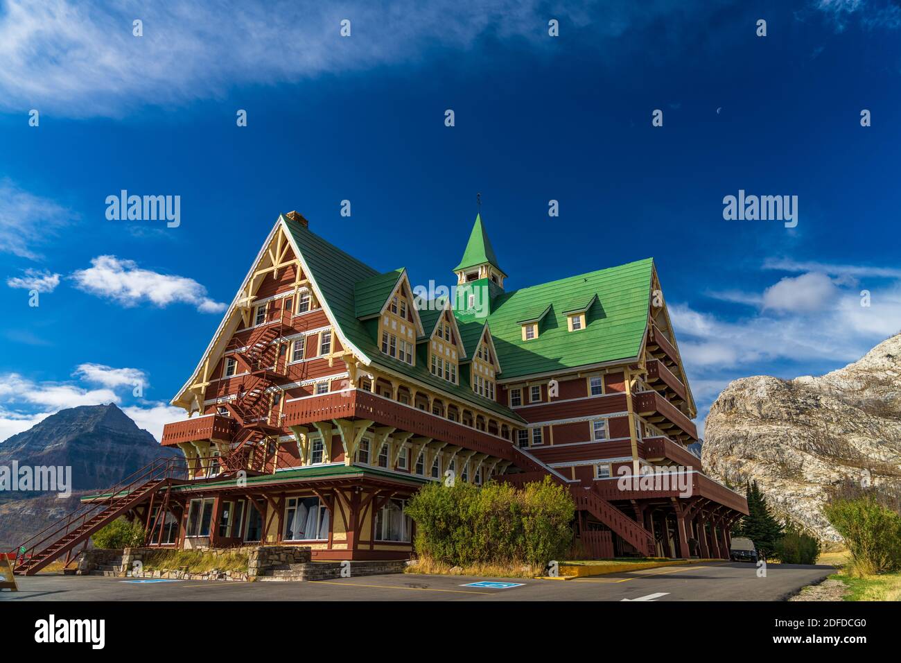 Prince of Wales Hotel im Herbst sonnigen Tag Morgen. Blauer Himmel, weiße Wolken über Bergen im Hintergrund. Wahrzeichen im Waterton Lakes National Park Stockfoto