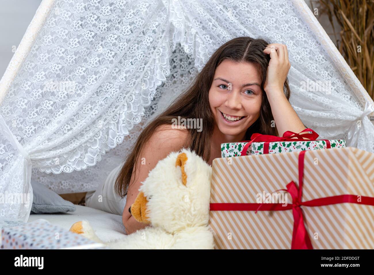 Brunette Teenager-Mädchen zwischen weihnachten Geschenk-Boxen und Spielzeug liegen, Weihnachtskonzept Stockfoto