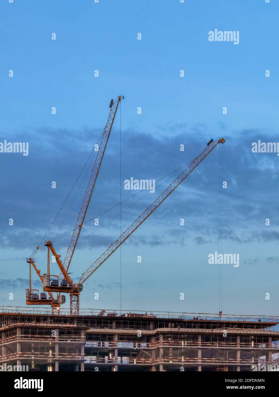 Baukräne über einem Gebäude im Bau symbolisieren die Konstruktion Boom in städtischen Gebieten und Urbanisierung mit der Bevölkerungsverschiebung Von Stockfoto