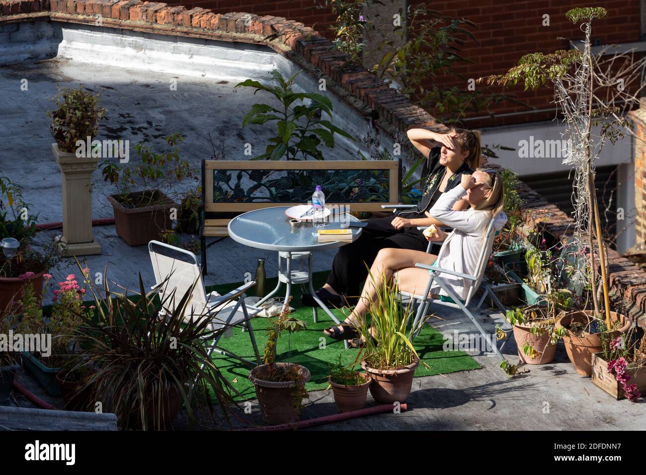 Zwei Mädchen, die sich während der COVID-19 Pandemie in Brixton, London, in einem behelfsmäßigen Dachgarten entspannen Stockfoto