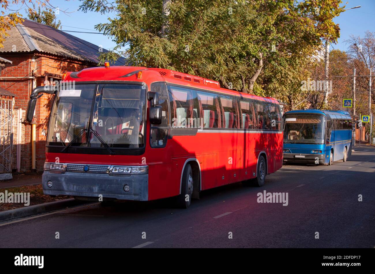 Zwei rote und blaue Personenbusse stehen entlang der Straße Geparkt Stockfoto