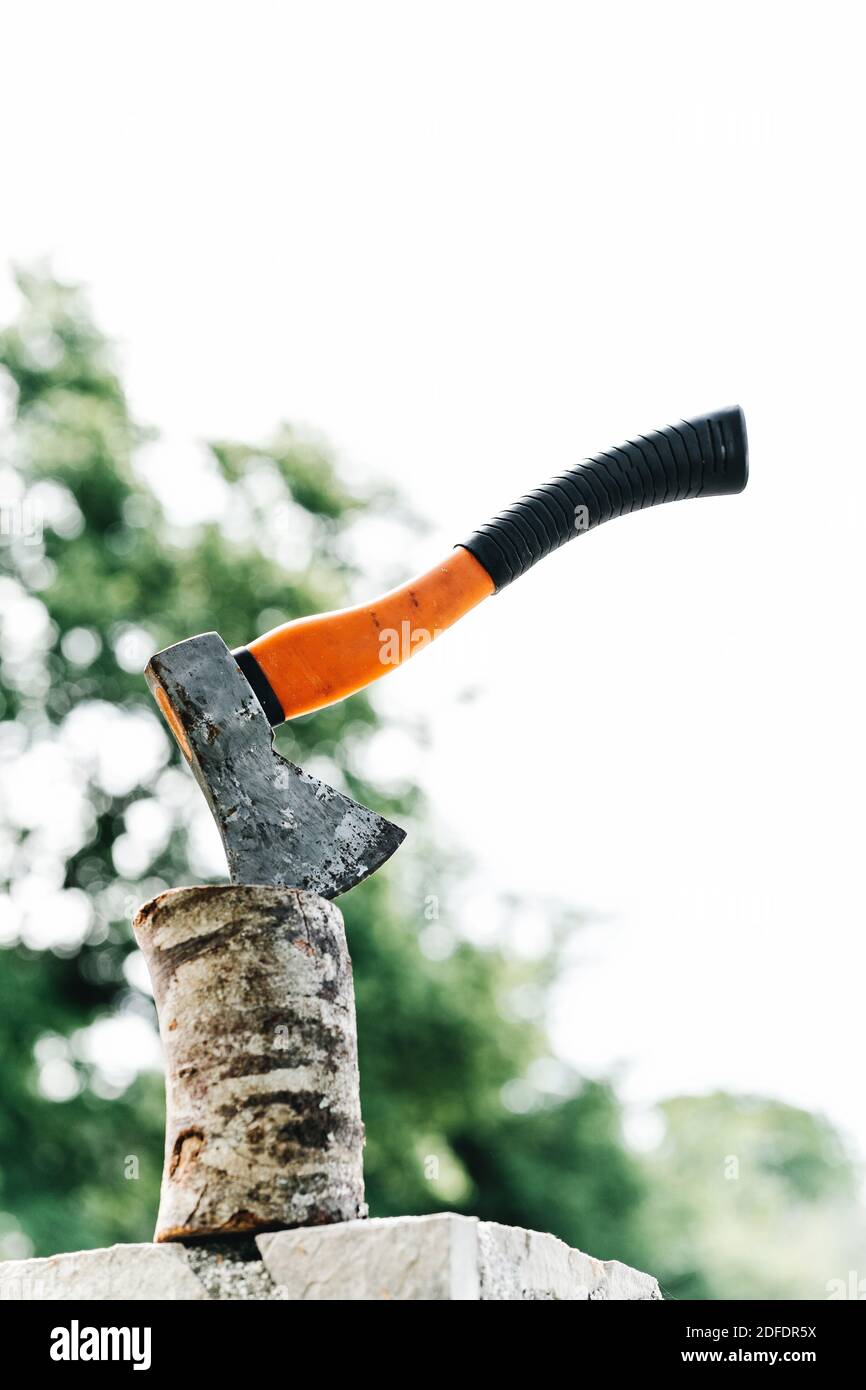 Axt mit orangefarbenem Griff ragt in Hanf aus Stockfoto
