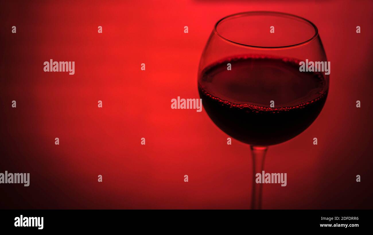 Glas Rotwein Platz für Text, Rotwein in einem Glas auf einem bunten rosa Hintergrund. Stockfoto