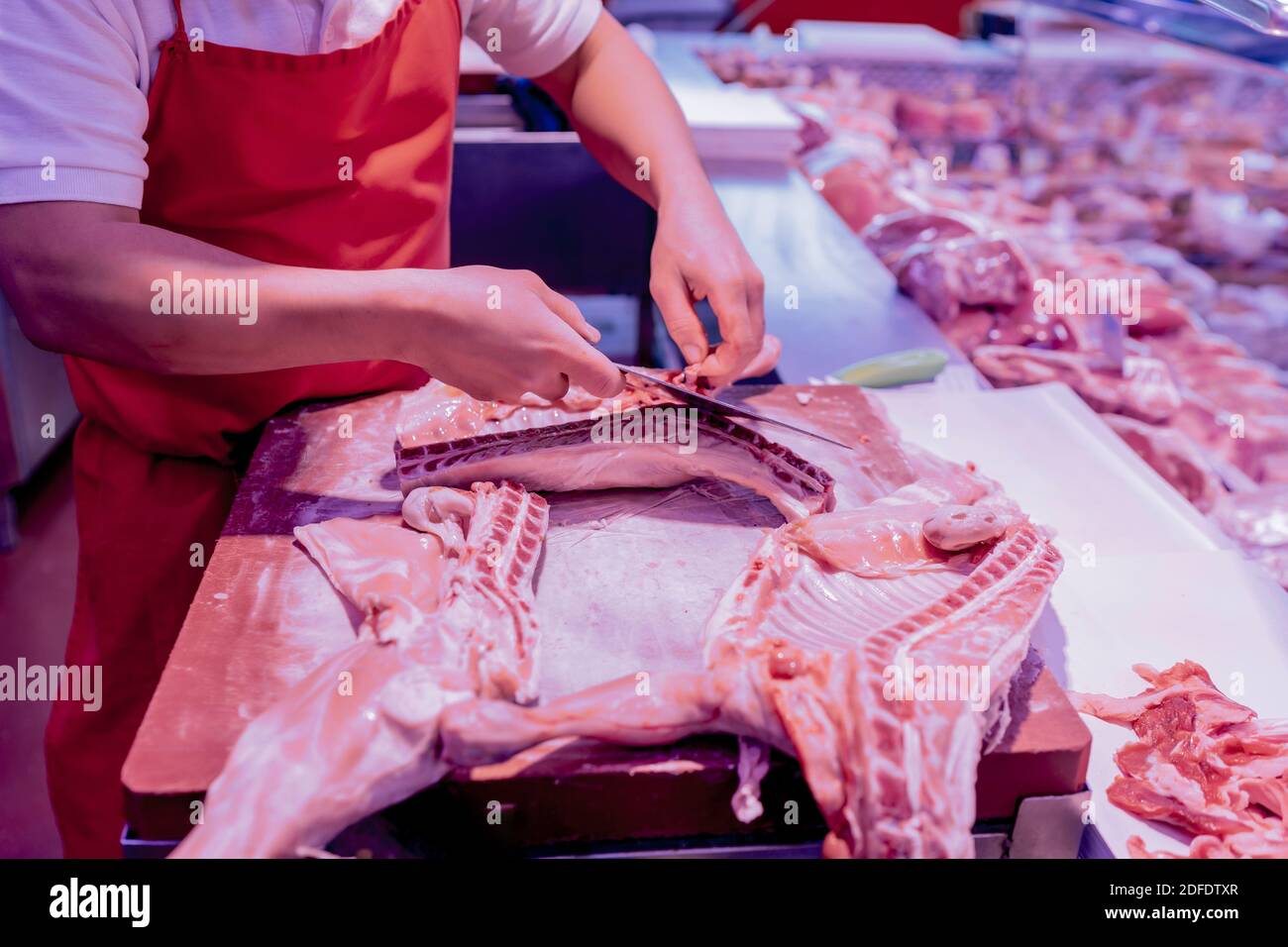 Metzger schneidet Milchlammfleisch Stockfoto