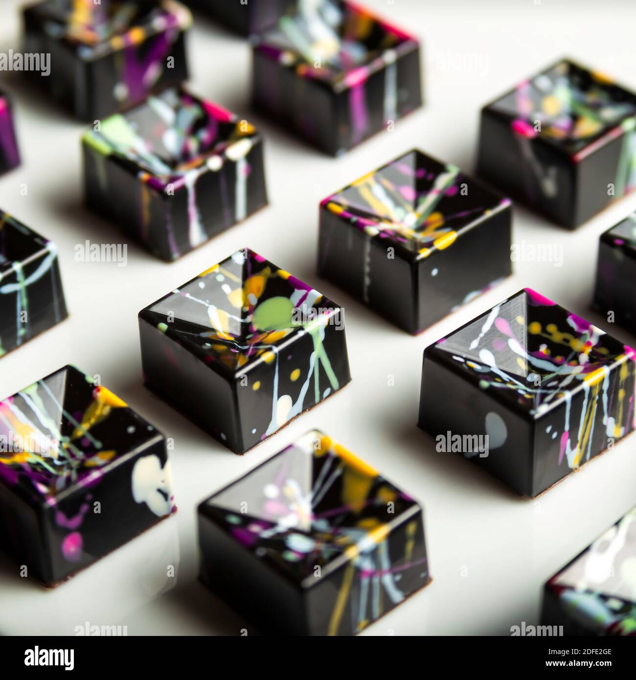 Luxus Schokolade handgemachte Bonbons mit Ganache mit bunten abstrakten Kunst auf weißem Hintergrund dekoriert. Exklusiver handgefertigter Bonbon Stockfoto