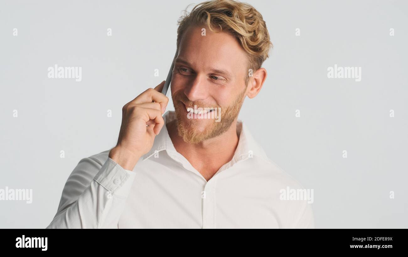 Schöner lächelnder bärtiger Mann im Hemd diskutiert neues Business-Projekt sprechen auf Smartphone isoliert auf weißem Hintergrund. Moderne Technik Stockfoto