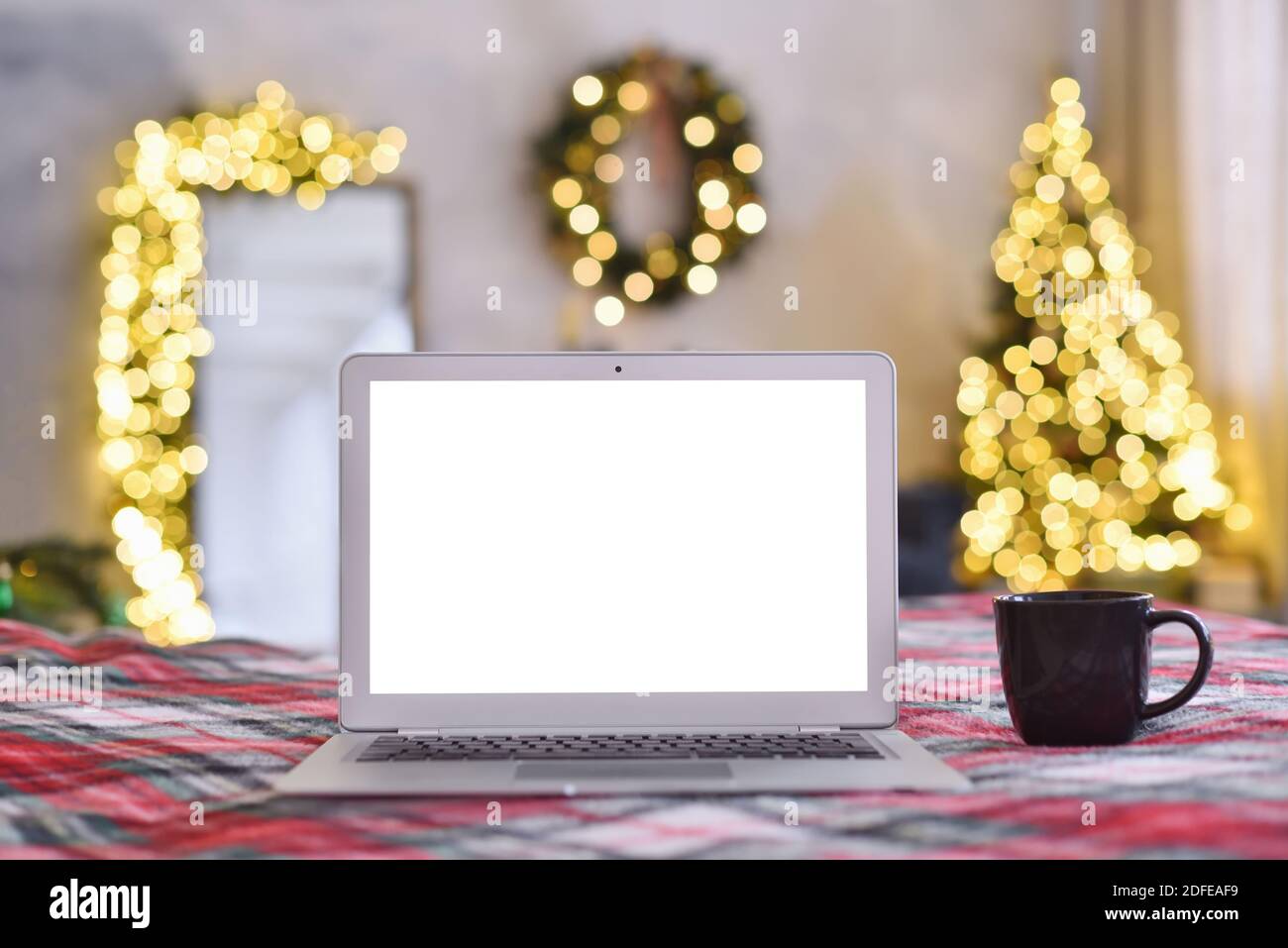 Laptop mit leerem Bildschirm in einem gemütlichen weihnachtlichen Interieur Stockfoto