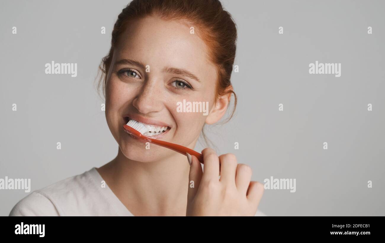 Attraktive lächelnde Mädchen glücklich Blick in der Kamera Zähneputzen über Weißer Hintergrund Stockfoto