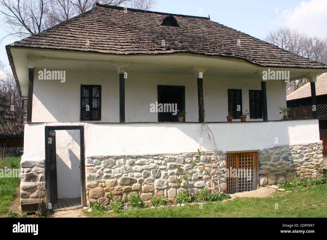 Das Dorfmuseum, Bukarest, Rumänien. Holzhaus aus dem 19. Jahrhundert aus der Grafschaft Arges, mit Holzschindeldach, Balkon, Steinfundament und Keller. Stockfoto