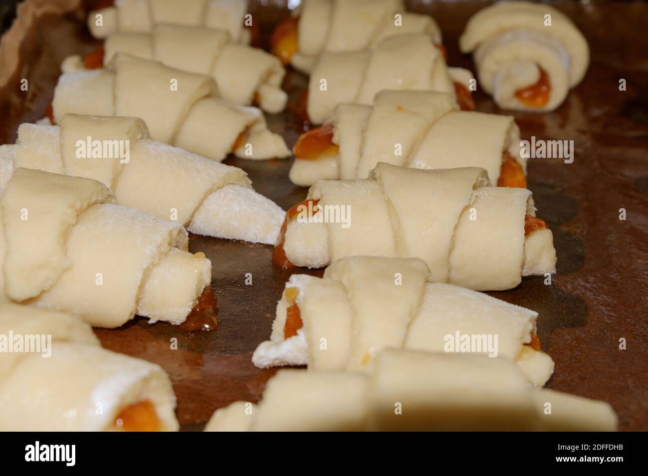 Hausgemachte Kekse in ein Rohr mit Marmelade Füllung gerollt auf einem Backblech mit einer Rückseite aus Papier mit Pflanzenöl befeuchtet ausgelegt. Selektiver Fokus. Stockfoto