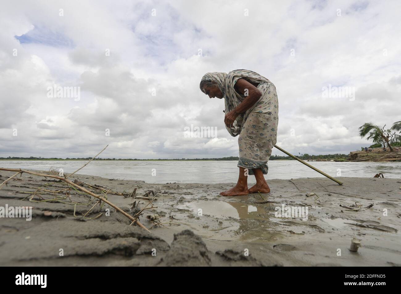 Vanu Bibi, 101 Jahre alt, die vor 15 Tagen aufgrund von Flusserosion ihr Zuhause verloren hat, spaziert am Ufer des Dhaleshwari-Flusses in Keraniganj, in der Nähe von Dhaka, Bangladesch, 17. August 2020.Bangladesch ist eines der bevölkerungsreichsten Länder der Welt mit 32% Küstengebiet, das 47,211 Quadratkilometer beträgt, 35 Millionen Menschen leben in der Küstenregion, was 28 % der Gesamtbevölkerung ausmacht. Insbesondere die Übernutzung und Verschmutzung der Wasserressourcen und der biologischen Vielfalt haben nach Angaben der spezialisierten Entwicklungsaktivitäten der Menschheit die Risiken der Katastrophen infolge von Klimaveränderungen erhöht Stockfoto